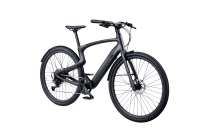 Urtopia Carbon 1 E-Bike in Frontansicht mit Carbonrahmen, LED-Display, Fingerabdrucksensor, Blinkerprojektion und StVZO-konformer Beleuchtung.