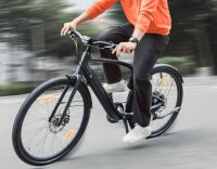 Urtopia Carbon 1 in Aktion beim dynamischen Abbiegen mit einer Person auf dem eBike.