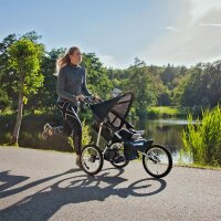 Frau joggt bei Sonnenschein mit einem dreirädrigen...