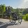 Frau joggt bei Sonnenschein mit einem dreirädrigen Jogger-Kinderwagen am See entlang