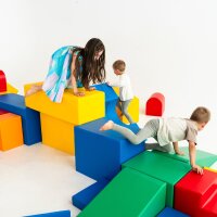 Kinder spielen auf bunten, geometrischen Spielblöcken in einem hellen Raum