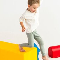 Kind balanciert spielerisch auf einer gelben, geometrischen Form