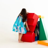 Mädchen in buntem Kleid spielt mit farbenfrohen Spielblöcken