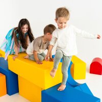 Kinder spielen auf bunten, geometrischen Spielblöcken in verschiedenen Farben