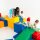 Kinder spielen auf bunten, geometrischen Spielblöcken in einem hellen Raum