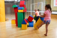 Kinder spielen mit bunten, geometrischen Bauklötzen in einem Raum