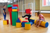 Kinder spielen mit bunten, geometrischen Bauklötzen in einem Raum