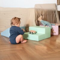 Kleines Kind spielt mit Spielzeug auf bunten Schaumstoffblöcken
