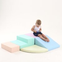Kind sitzt auf bunten Schaumstoffspielmodulen in verschiedenen Formen und Farben
