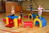 Kinder spielen auf bunten, weichen Kletterelementen in einer Sporthalle