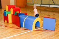 Bunte Schaumstoffbausteine in einer Turnhalle, Kind spielt damit