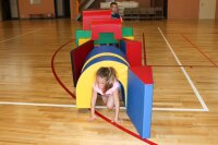 Kinder spielen mit bunten Schaumstoffbausteinen in einer Turnhalle