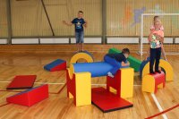 Kinder spielen auf bunten Kletterelementen in einer Sporthalle