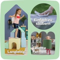 Kind sitzt auf buntem Spielblock mit verschiedenen Formen und Texturen