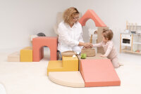 Kinder spielen an einem weißen Tisch mit Bauklötzen auf einem Teppich