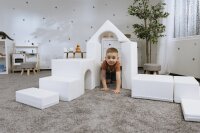 Kind spielt mit weißen Schaumstoffbausteinen in einem Spielzimmer