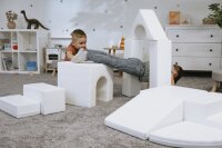 Zwei Kinder spielen mit weißen Bauklötzen in einem Spielzimmer