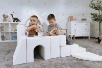 Zwei Kinder spielen mit Bauklötzen in einem Spielhaus aus Schaumstoff