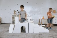 Zwei Kinder spielen mit weißen Bausteinen in einem Spielzimmer