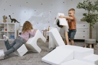 Kinder spielen mit weißen Schaumstoffbausteinen im Spielzimmer