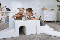 Zwei Kinder spielen mit Bausteinen in einem hellen Raum