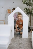 Kind spielt in einem Spielbereich mit weißen Schaumstoffbausteinen