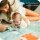 Mutter spielt mit Baby auf buntem Spielteppich im Innenraum